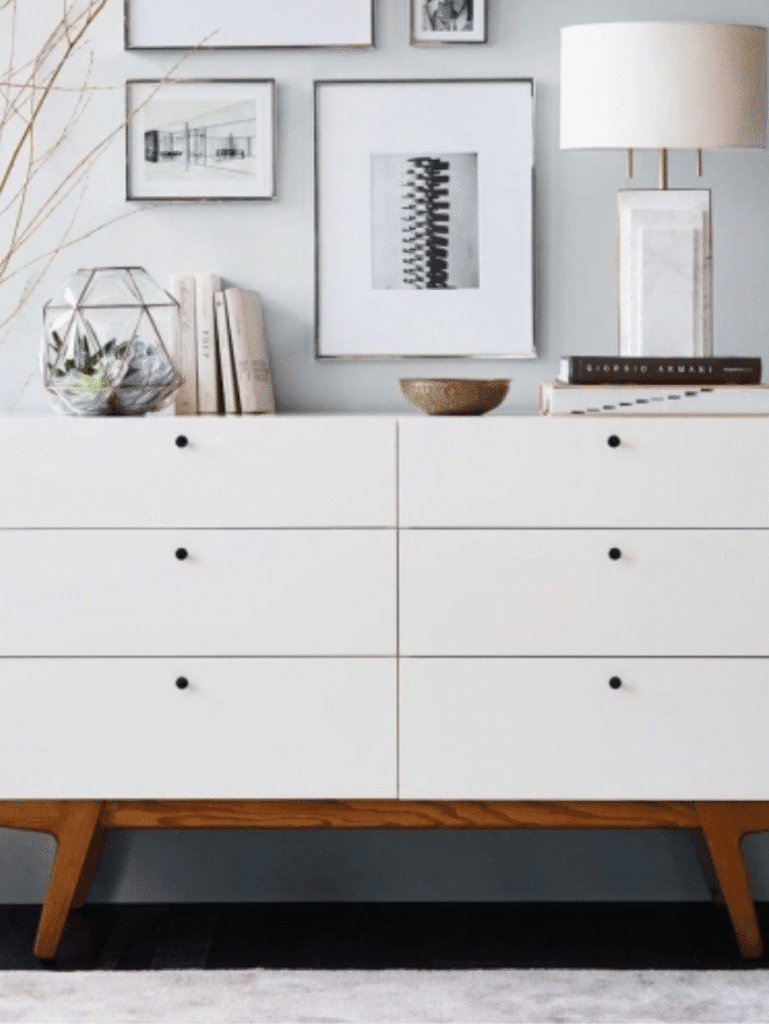 Minimalist white dresser with black drawer pulls in a modern bedroom.