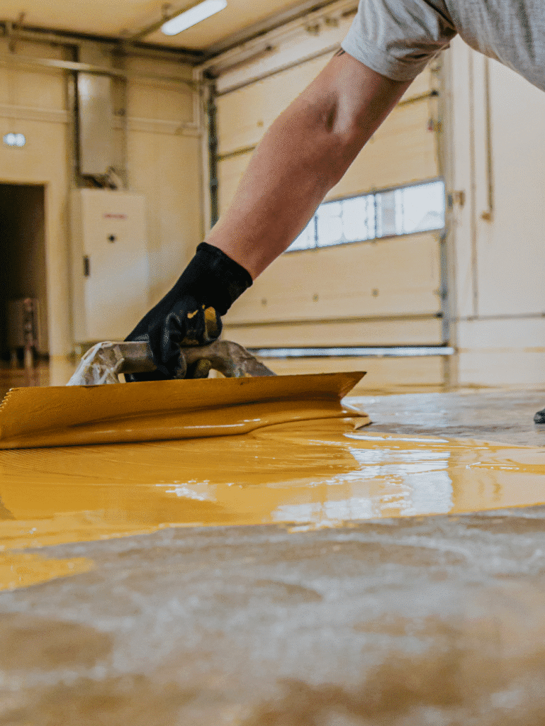 Worker applying epoxy flooring in an industrial space